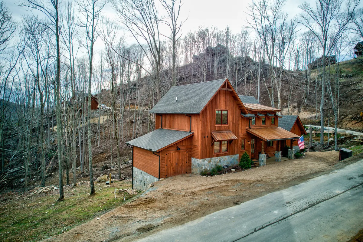 An exterior shot of a spacious wooden house, with an American flag and surrounded by tall trees. The image hints at space for family gatherings, nature walks, and outdoor barbecues, while the sunset light adds a celebratory, welcoming mood.